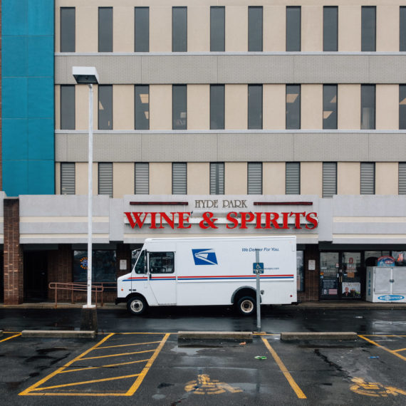 A mail truck in front of a store with a sign that reads WINE & SPIRITS