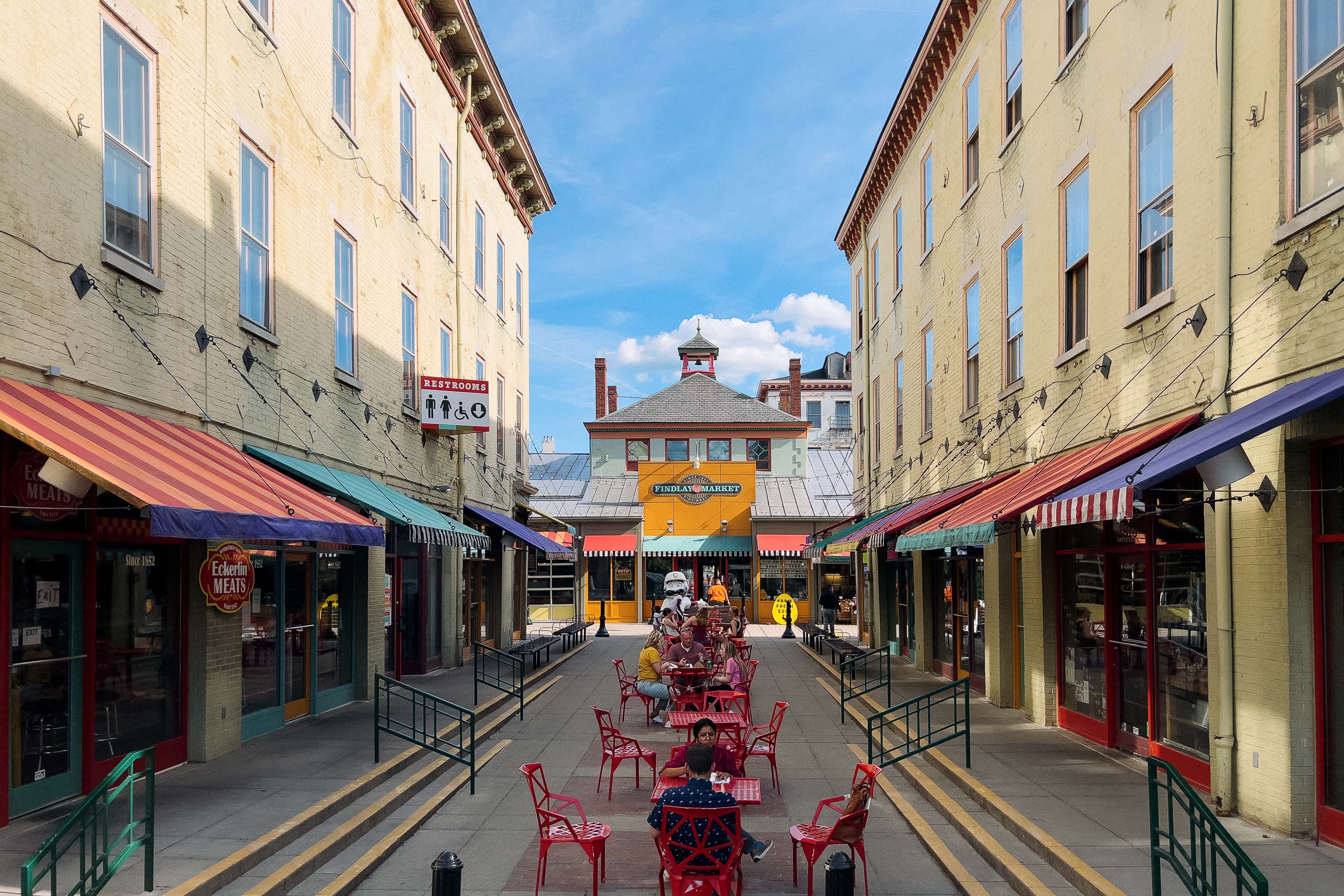 A public farmers market with colorful awnings and outdoor seating