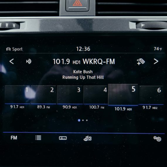 A car radio with a touchscreen interface of the radio displaying the song "Running Up That Hill" by Kate Bush