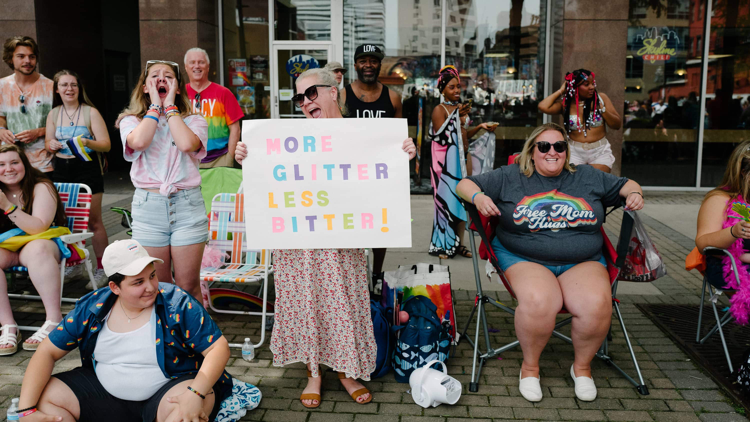 A woman holds a sign that reads "More glitter, less bitter"