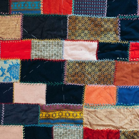 An unfinished quilt made of colorful rectangular pieces of fabric