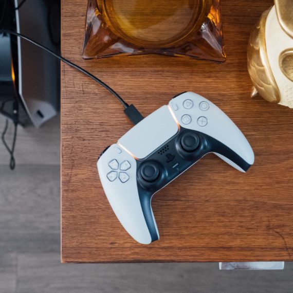 A white game controller rests charging on a wood table