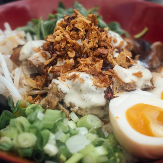 Lemongrass chicken rice bowl with scallions, soft-boil egg, fried onion and cilantro