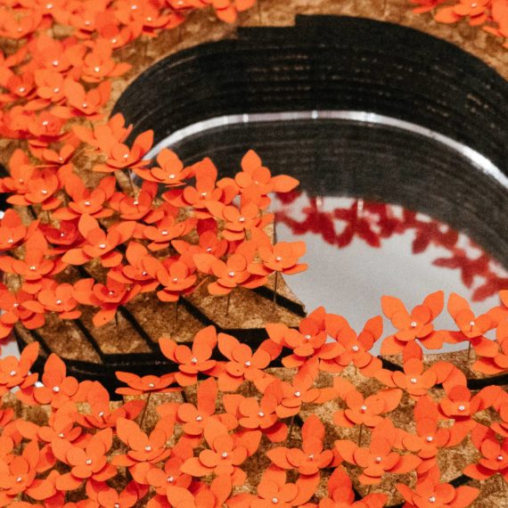 A diorama of trees with orange blooms surrounding a small lake made with a mirror