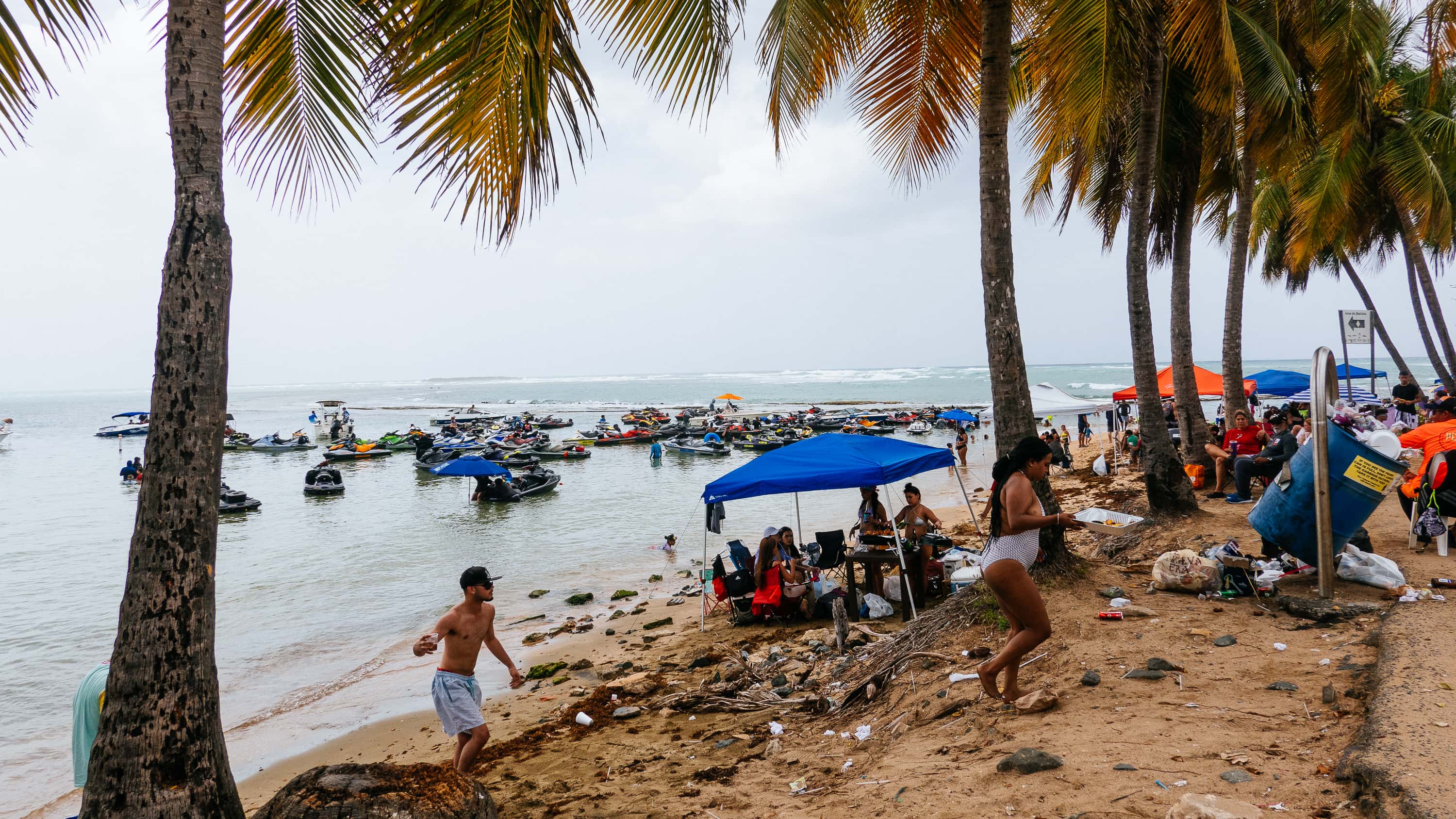 Boats and jet skis off the beach of Piñones, Puerto Rico while the beach is dotted with tents and revelers (and trash)