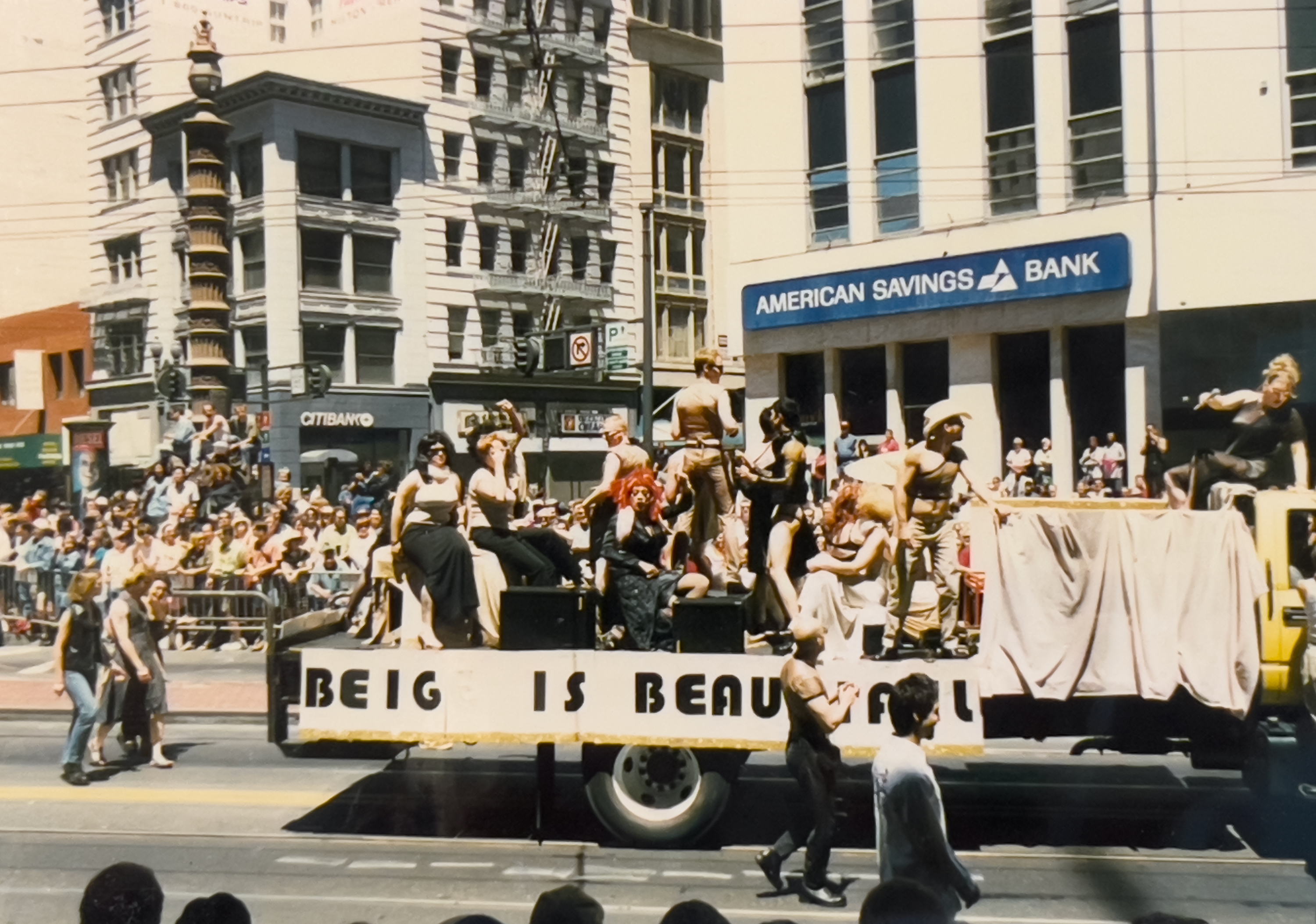 An old photograph of a Gay Pride Parade in San Francisco in the late 90's. A float that reads BEIGE IS BEAUTIFUL is filled with folks wearing beige clothing