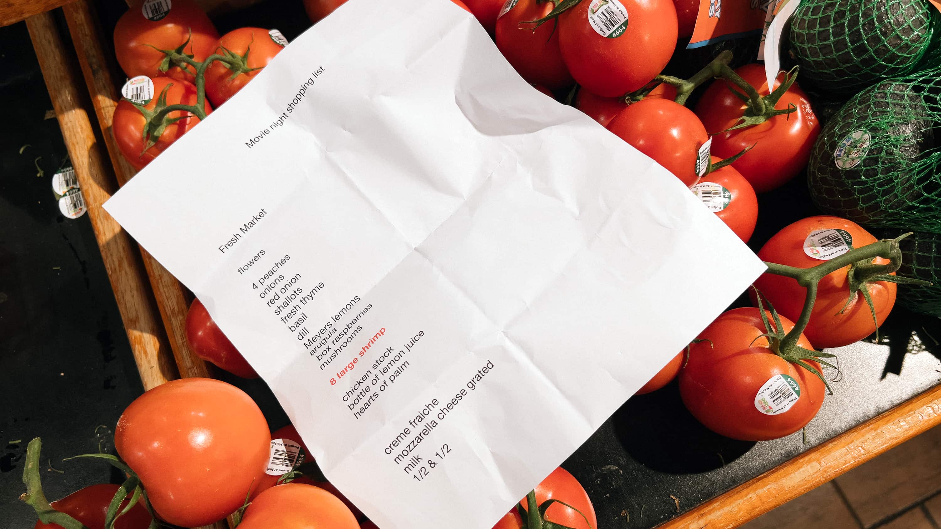 A list of items to pick up at the grocery store for movie night left behind on tomatoes