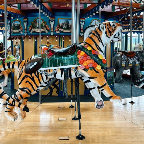 A tiger with a saddle and football decoration on a carousel