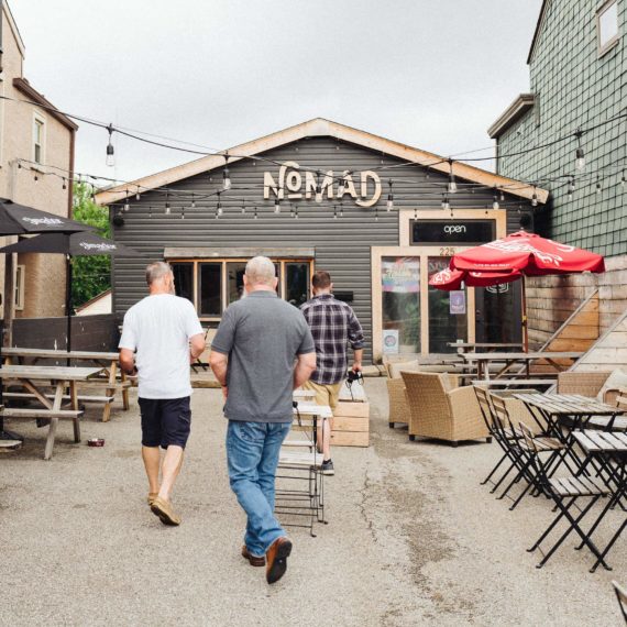 Three men walk toward a restaurant called NOMAD