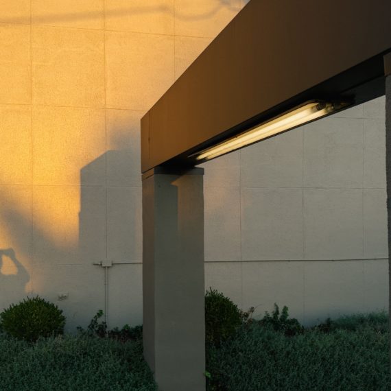 Setting sun casts shadow from a geometric arch with fluorescent lights