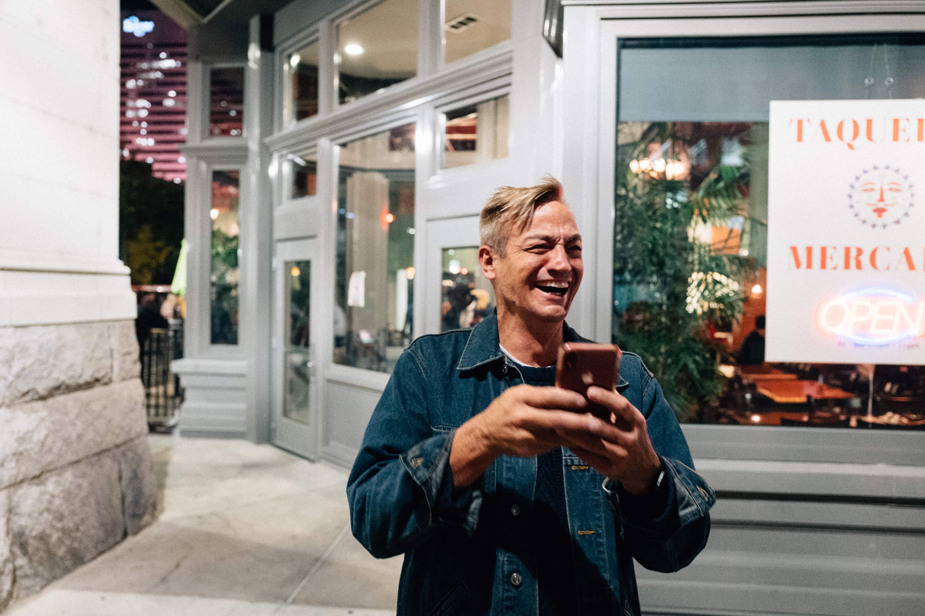 a man laughs while holding a mobile phone