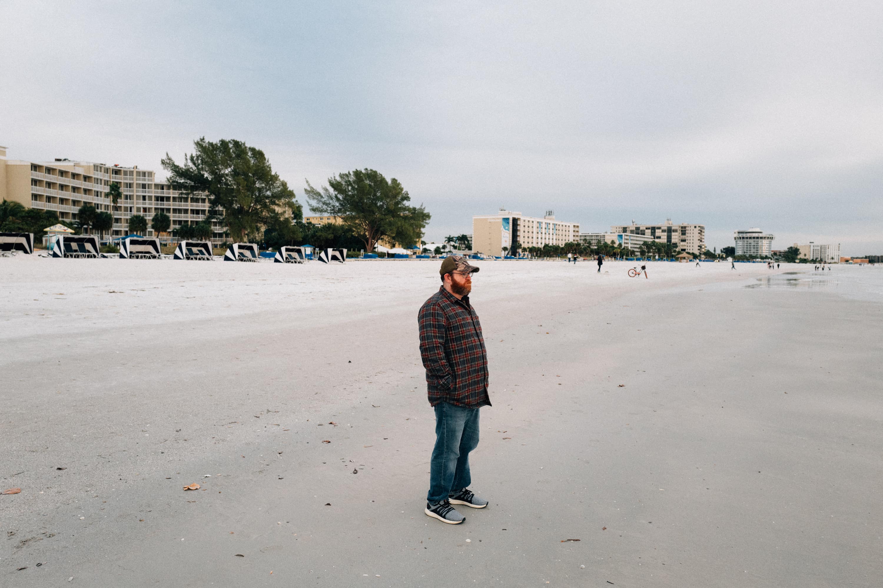 A man stands on a beach with a winter coat on