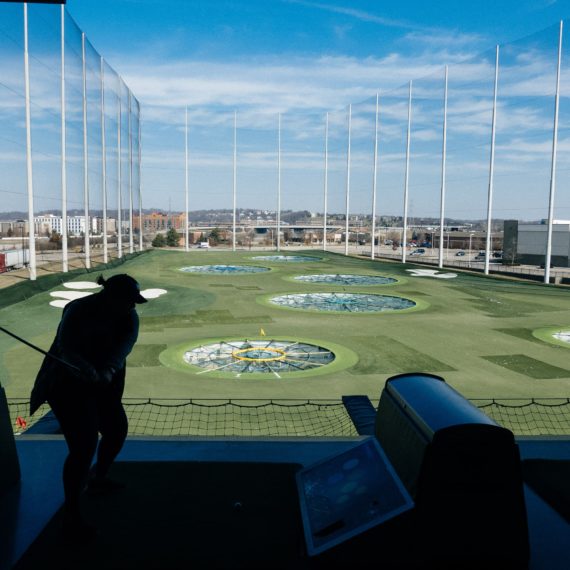 A woman swings a golf club at one of those golf places