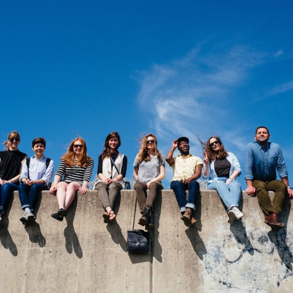 Folks sit on top of a concrete wall