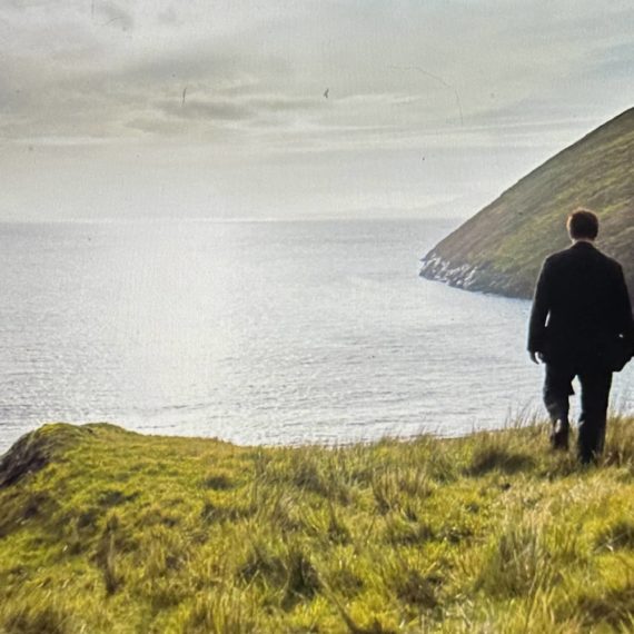 A man walks toward a rural coast in Ireland