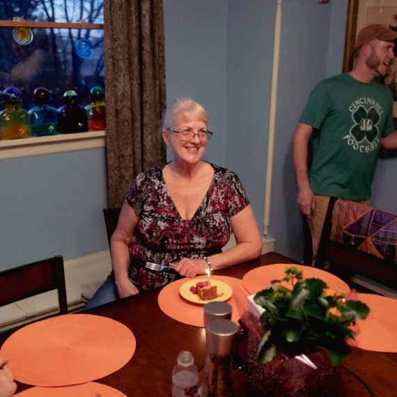 Woman gets ready to blow out birthday candle on slice of cheesecake