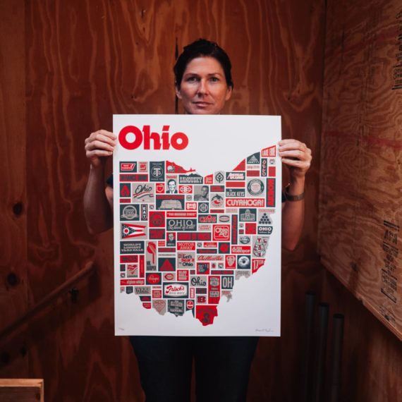 Kelley Deal holds a poster about Ohio designed by Aaron Draplin