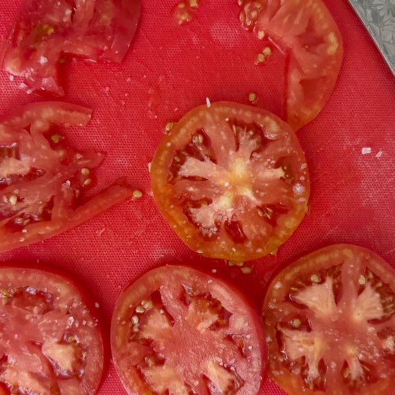 sliced tomatoes on a red cutting board