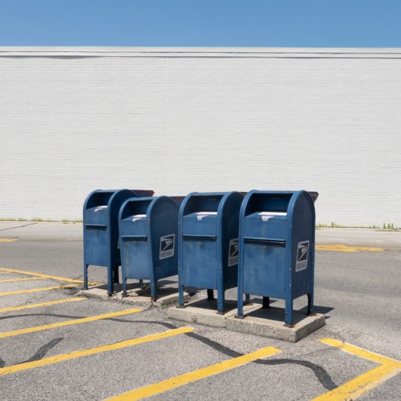 Four drive-up mail boxes in a parking lot outside a post office