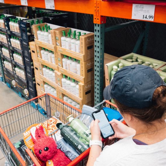 Person checks grocery list on phone while in a Costco