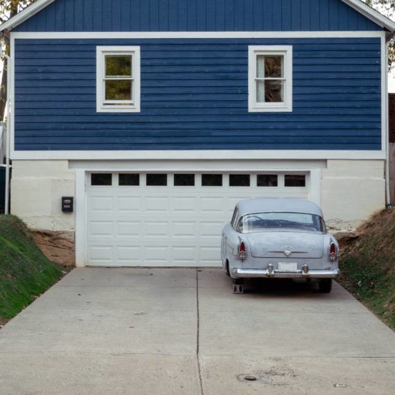 Old car in a driveway propped up on a brick