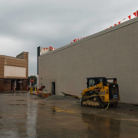 A small bulldozer on the side of a building in a strip mall