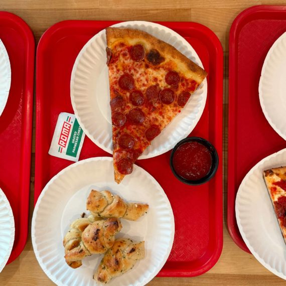 Slices of pizza on paper plates on red trays