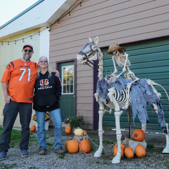 Brother and sister in Bengals gear next to a skeleton riding a skeleton horse decoration