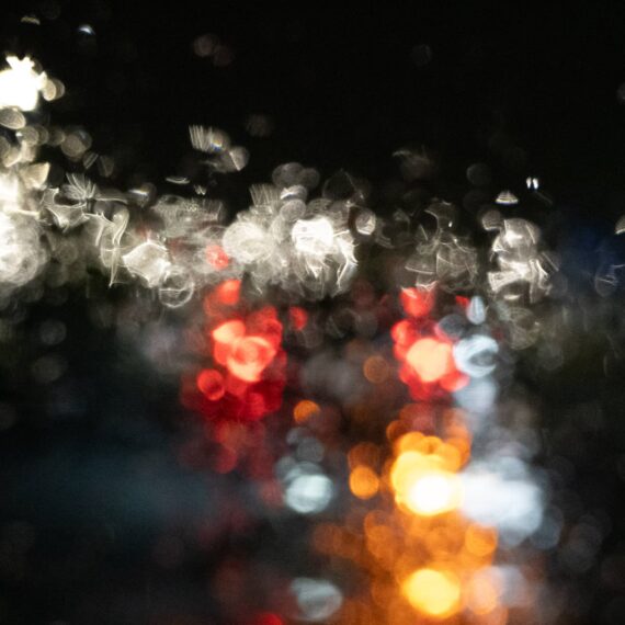 Blurry car lights through windshield covered in raindrops