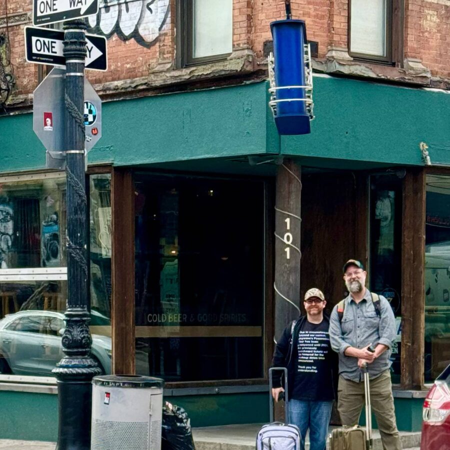 Two men under the Beastie Boys Square street sign intersection