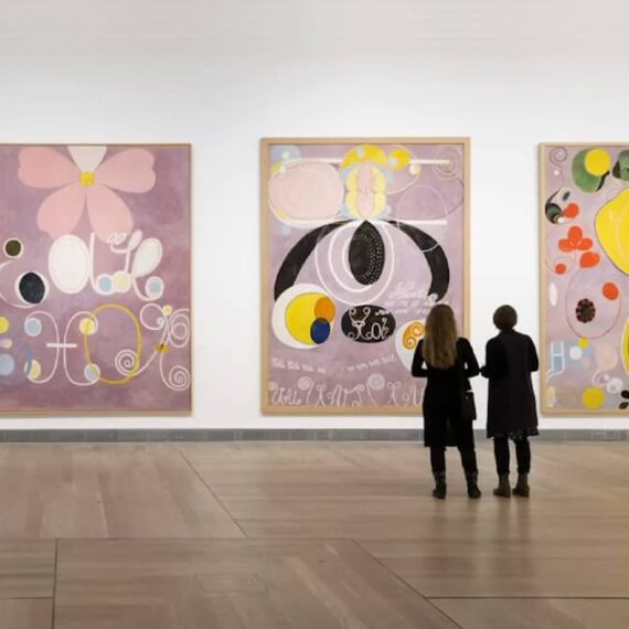 Two figures view large artworks by Hilma af Klint